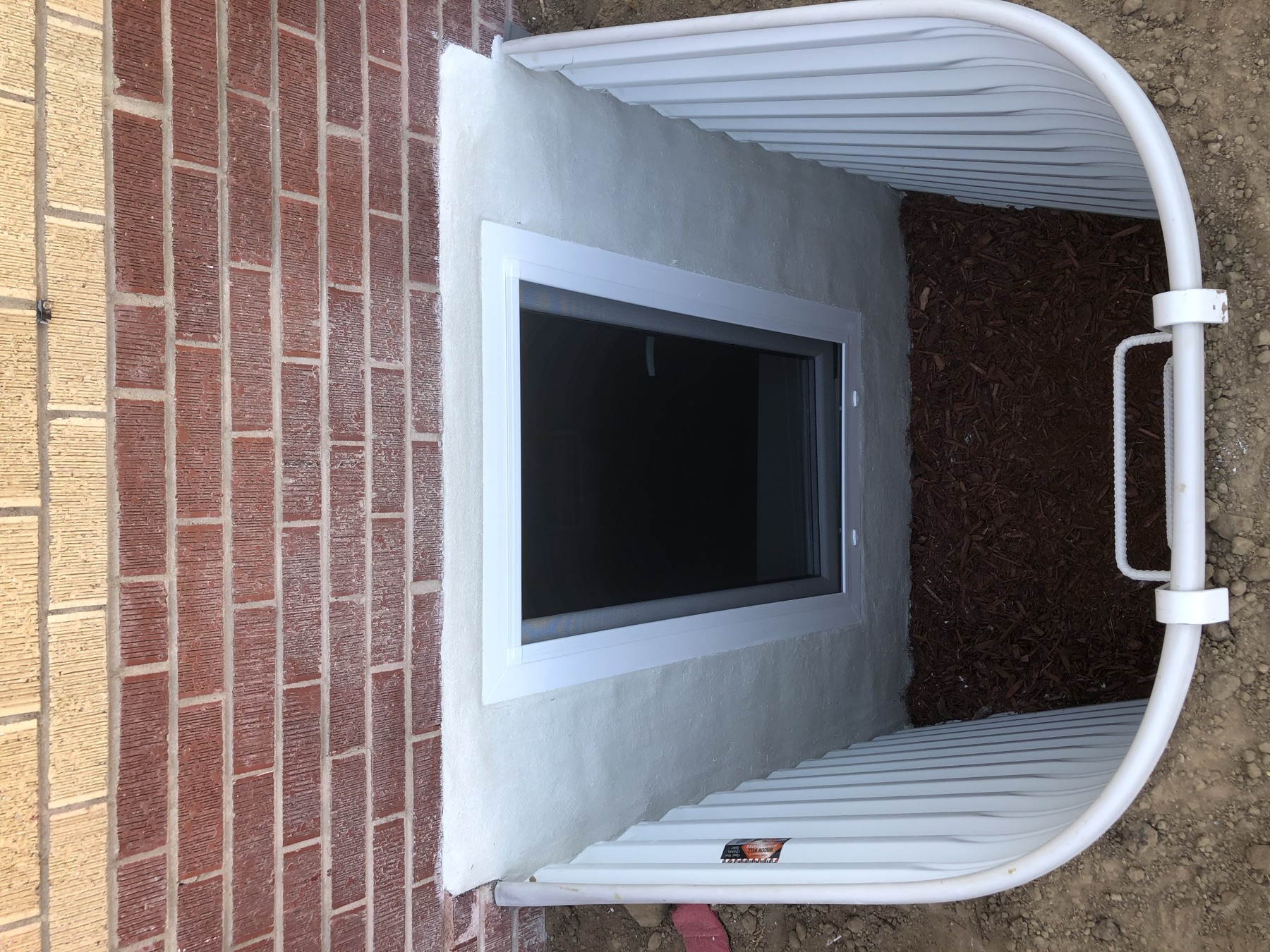 Completed egress window installation brick home Colorado